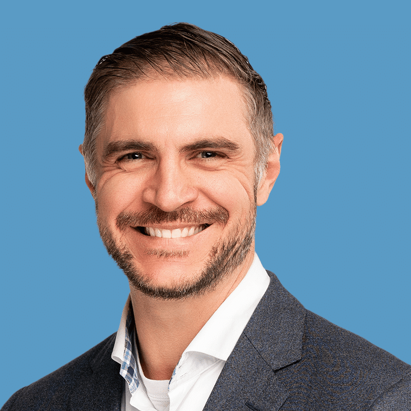 Headshot of Beau Langston, a smiling man with brown and gray hair and beard wearing a suit against a blue background.